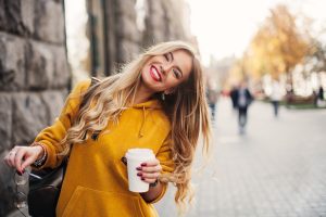 young woman in a yellow sweater smiling, showing off her white smile