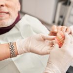 dentist showing a pair of dentures to a patient