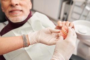 dentist showing a pair of dentures to a patient