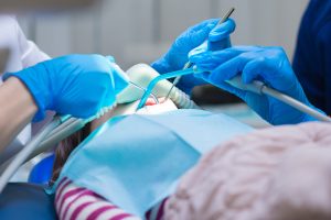 doctors in blue gloves providing sedation during a dental procedure