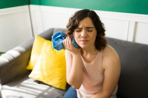 young woman sitting on a couch with an ice pack, serious tooth pain